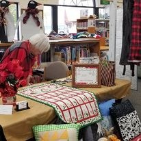 Vendor with homemade crafts including pillows, ponchos and table runners